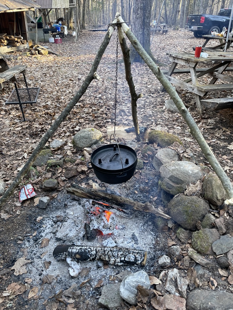 A cast-iron pot suspended over a campfire.