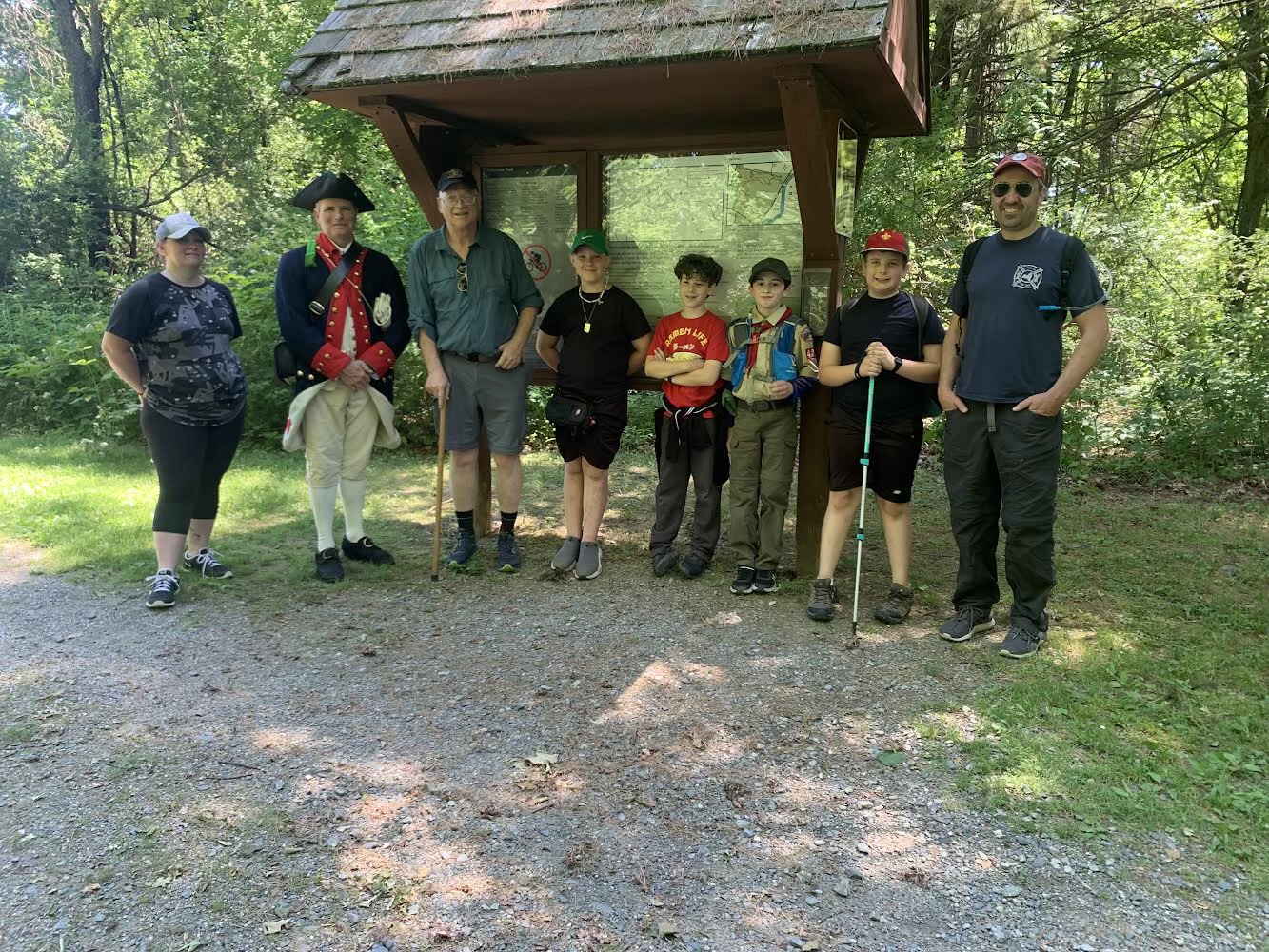 Scouts and adult leaders gathered at a forest trailhead.
