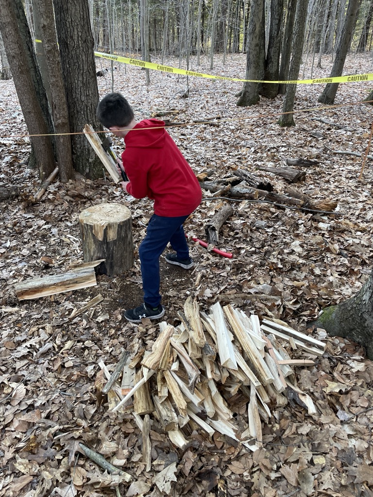 A Scout splitting kindling for a campfire.